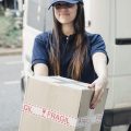 portrait-courrier-feminin-souriant-boite-carton-scaled